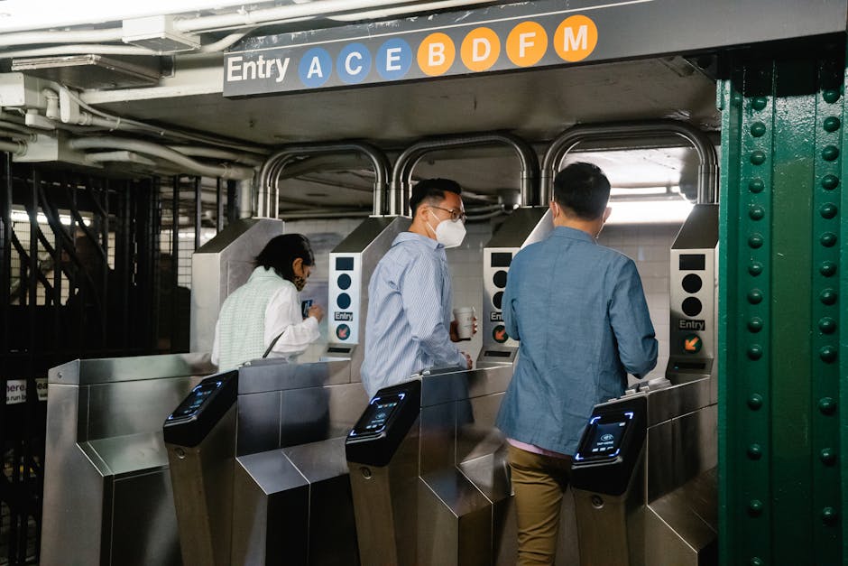 People using turnstiles at a subway station entry in urban setting.